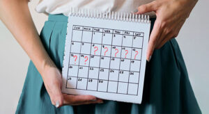 زنی در حال تجربه علائم جسمی و روحی سندرم پیش از قاعدگی (PMS)